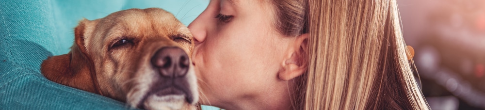 woman kissing sad dog